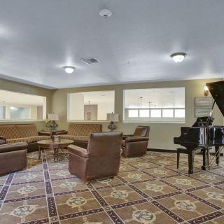 A cozy lounge area featuring comfortable seating, a grand piano, and decorative floor tiles.