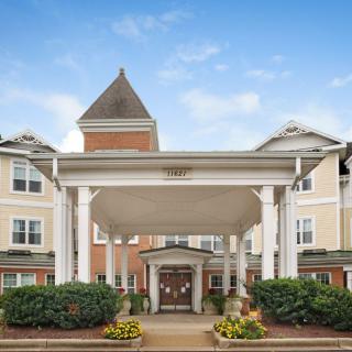 A view of a large building entrance with columns and landscaping.