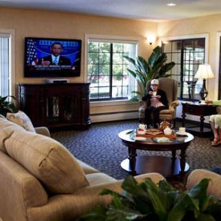 A cozy living room with people relaxing, featuring a TV, sofas, and a coffee table.