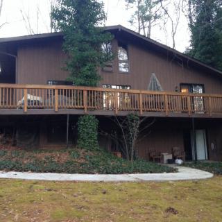 A rustic house with a wooden deck surrounded by trees.