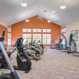 A spacious gym room with cardio machines and bright lighting.