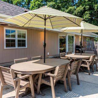 A cozy outdoor patio with tables, chairs, and umbrellas ready for a sunny gathering.