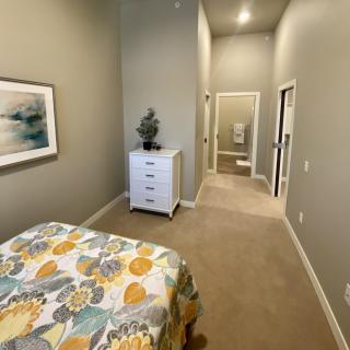 A modern bedroom with a floral bedspread, dresser, and wall art.