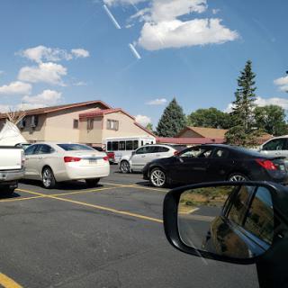 A busy parking lot filled with cars and a view of nearby buildings under a clear blue sky.