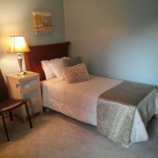 A cozy bedroom with a single bed, nightstand, and lamp.