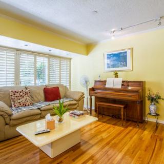 A cozy living room with a sofa, piano, and coffee table on a hardwood floor.