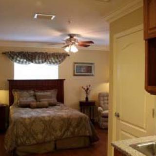 A cozy bedroom with a large bed, ceiling fan, and window with curtains.