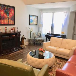 A cozy living room with modern furniture, featuring a piano and colorful artwork.