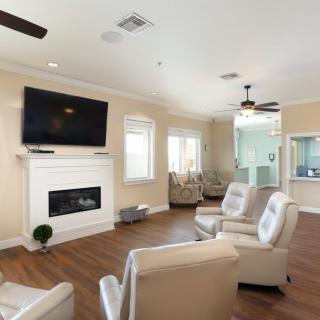 A modern living room with a fireplace, television, and comfortable seating on a wooden floor.