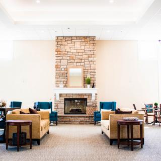 A modern living room with a central fireplace surrounded by comfortable sofas and chairs.