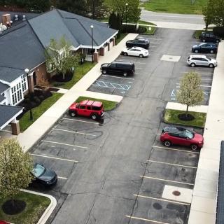 Aerial view of a parking lot next to residential buildings, featuring several parked cars.