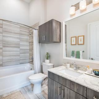 A modern bathroom with a sleek design featuring a bathtub, vanity, and simple decor.
