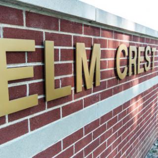A close-up view of the Elm Crest sign mounted on a brick wall.