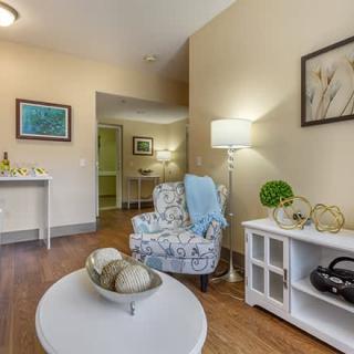 A cozy living room with a patterned armchair, a side table, decorative items, and wall art.