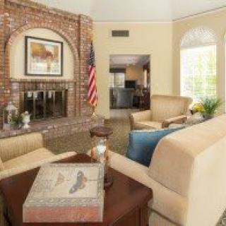 A cozy living room with a brick fireplace, comfortable seating, and a decorative flag.