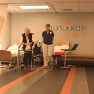 An elderly patient receiving assistance during rehabilitation at a healthcare facility.