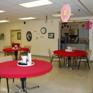 A simple cafeteria with tables covered in red tablecloths, decorated with hanging ornaments.