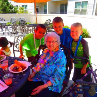A family gathering outdoors with an elderly woman and children enjoying a meal together.