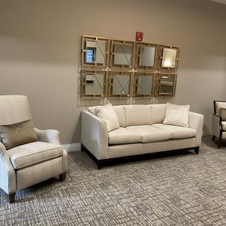 A cozy living room setup with a sofa, armchair, and decorative mirrors on the wall.