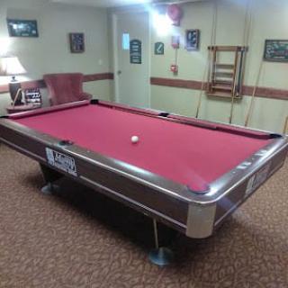 A billiards room with a red-felt pool table and various decor.