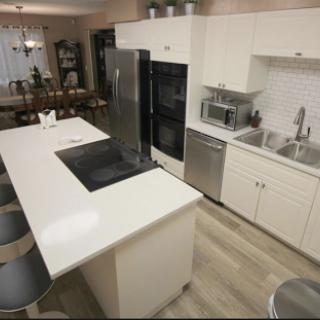 A modern kitchen showcasing a sleek design with white cabinetry and an island for cooking and dining.