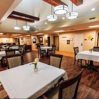 A well-lit dining area with neatly arranged tables and chairs, featuring elegant lighting fixtures.