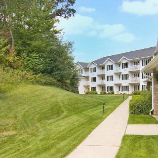 A well-maintained apartment complex with a lush green lawn and surrounding trees.