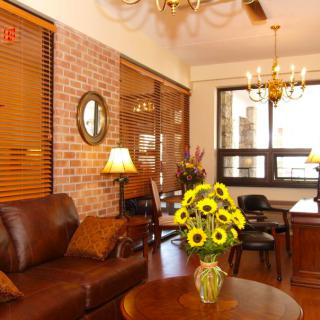 A cozy living room with a brick wall, leather sofa, and sunflowers on a wooden table.