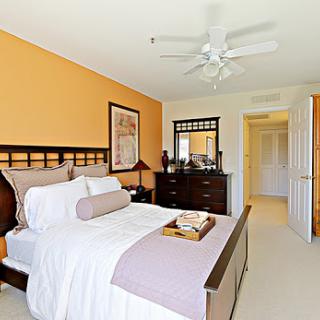A beautifully designed bedroom featuring vibrant orange walls, a comfortable bed, and stylish furniture.