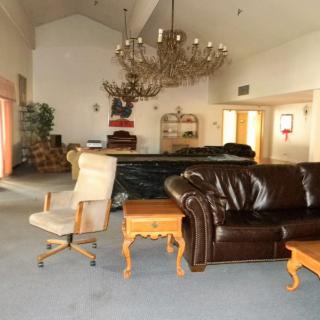 A spacious living area with various pieces of furniture, including couches, chairs, and a chandelier.