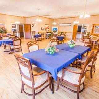 A spacious dining area with tables covered in blue tablecloths and decorated with flower arrangements.