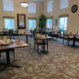 A spacious dining room with neatly arranged tables and chairs, featuring large windows and elegant decor.