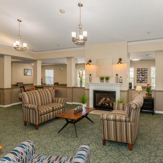 A cozy living room with striped sofas, a fireplace, and chandeliers.