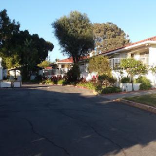 A peaceful residential area showcasing well-maintained gardens and trees along a winding pathway.