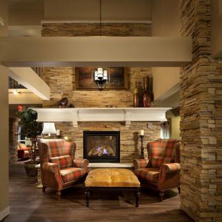 A cozy lounge featuring a stone fireplace surrounded by wooden furniture.