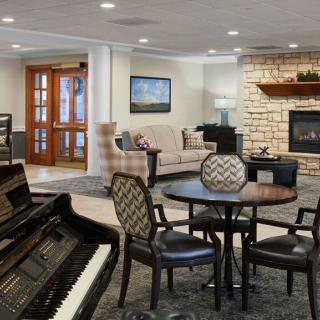 A cozy living room with a piano, seating area, and fireplace.