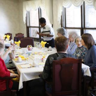 A group of senior citizens enjoying a meal together while being served.
