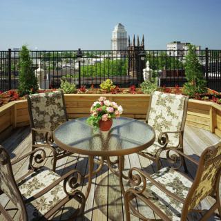 A sunny rooftop patio with elegant furniture and a cityscape in the background.