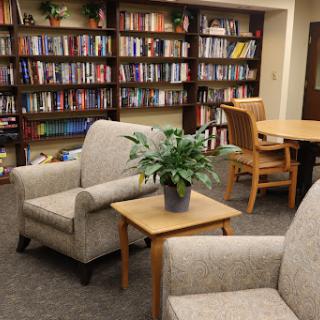 A cozy reading corner in a library, featuring comfortable chairs and a well-stocked bookshelf.