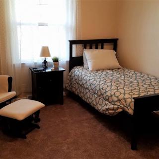 A cozy bedroom with a single bed, nightstand, and chair.