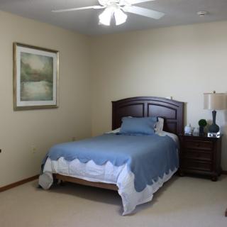 A neatly arranged bedroom with a bed, nightstand, and artwork on the wall.