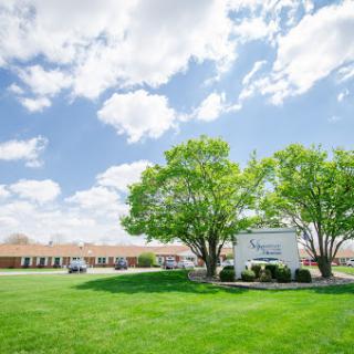 A welcoming entrance featuring lush green trees and a clear blue sky.