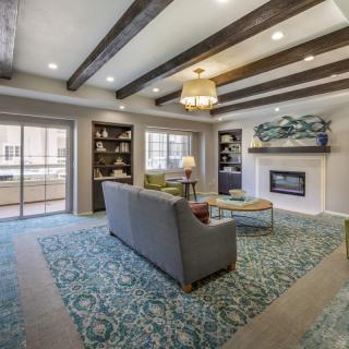 A modern living room with a cozy fireplace, stylish furniture, and exposed ceiling beams.