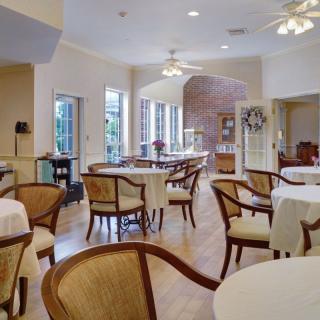 A cozy dining area with neatly arranged tables and chairs, bathed in bright natural lighting.