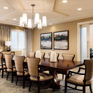 An elegantly designed dining room with a large table, surrounded by chairs and illuminated by a chandelier.