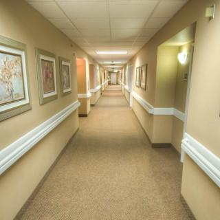 A long hospital corridor with framed artwork on the walls and bright overhead lighting.