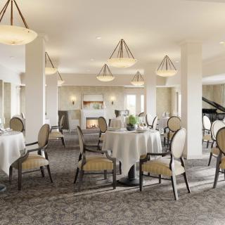 An elegant dining room with round tables, upholstered chairs, and ambient lighting.