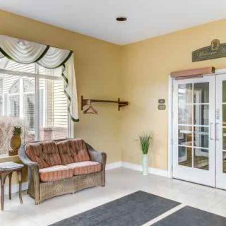 A cozy lobby area with a sofa, window with curtains, and glass doors.