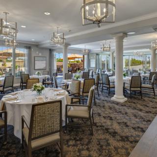 An elegant dining area with beautifully set tables and chandeliers overhead.
