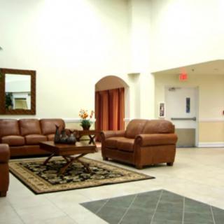 A well-furnished lobby area with leather sofas and a coffee table, complemented by a decorative rug and a wall mirror.